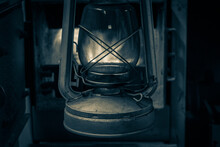 Antique Kerosene Lamp On A Wooden Stand Against The Background Of Fire In The Furnace. No Electricity