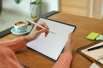 Young woman holding stylus pen and writing on digital tablet.