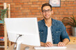 © dikushin - Portrait of confident cheerful handsome young freelance designer male in stylish glasses working on desktop computer sitting at desk at home office, in room with modern interior, looking at camera.