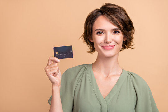 photo of cheerful happy young woman smile hold hands credit card buy shop isolated on beige color ba