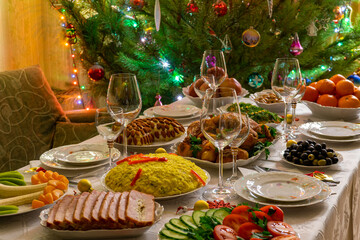 Festive Christmas served table against beautiful green pine tree decorated with many colorful new year toys. Xmas dinner, delicious food, christmas turkey. Winter holidays celebration at cozy home