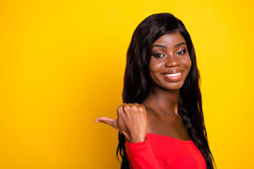 Poster - Photo of sweet shiny dark skin girl dressed red top pointing back empty space isolated yellow color background