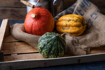 Canvas Print - Pumpkins lying on a straw sack in a wooden box