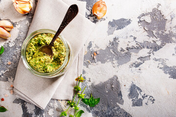 Canvas Print - Homemade parsley pesto sauce and ingredients on dark cement background. Close up wiev of basil pesto in glass jar with ingredients.