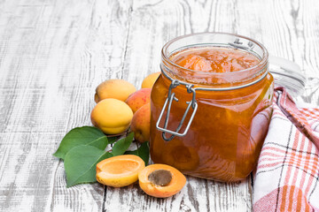 Wall Mural - Apricot jam in a glass jar on white wooden table