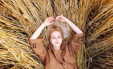 Sticker - Blonde woman in cloak and hat is lying on wheat field in countryside