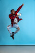 Studio shot of african man jumping and shouting at megaphone isolated over blue color studio background