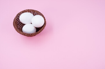 Poster - isolated white eggs in a wicker canister on a pink background with copy space