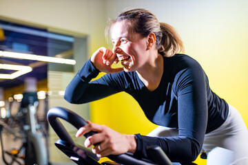 Wall Mural - Pretty authentic female instructor with headset in fitness class exercise with group in cycling room