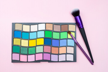 Palette with eyeshadows and makeup brushes on pink background. Flat lay. Blog about cosmetics and fashion. Set of products for makeup.