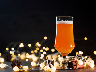 Canvas Print - A glass of Christmas beer ale on a dark background with a side garland and copyspace. Craft seasonal limited beer