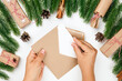 © Юля Бурмистрова - christmas card of woman hands sending letter to Santa Claus in frame of Christmas trees, cones, gifts and bundles of cinnamon.