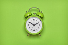 Green Alarm Clock On Light Green Background