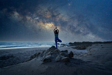 Silhouette Of A Woman Standing In Yoga Tree Position On The Rock Or Mountain With Milky Way Background	