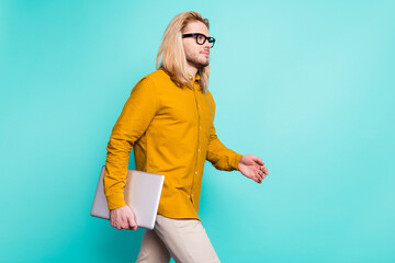 Profile side photo of young handsome man go walk step meeting hold laptop isolated over turquoise color background