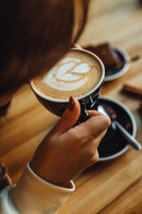 Women drinking Pumpkin spice latte at coffee shop; coffee and sweets on table. Seasonal coffe drinks