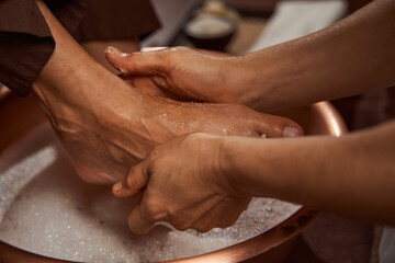 Wall Mural - Beauty salon worker rubbing her client feet with sea salt