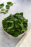 Fototapeta Tematy - Fresh spinach leaves in a bowl on gray background. Healthy food ingredient