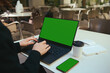 © Taras Grebinets - Rear view of female hands typing on laptop keyboard with green chroma key screen for ads. Mobile phone with green screen and copy space. Business, freelance, copywriting, online remote work concept