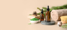 Christmas Spa Concept With Cosmetic Aroma Oil, Pine Cones, Evergreen Branches On Beige Background. Winter Holiday For Body Care And Wellness. Banner. Close Up.