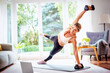 © gzorgz - Shot of sporty woman using a dumbbells while exercising at home