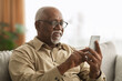© Prostock-studio - Senior Black Man Texting On Smartphone Using Application At Home