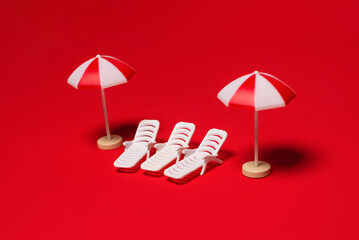 Two sun loungers and red umbrellas on a red background.