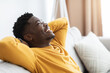 Closeup of cheerful black guy reclining on couch