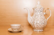 Juego de té con adornos dorados, pequeña taza de té con plato y tetera sobre un fondo de madera