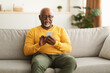 Senior Black Man Using Smartphone Texting Sitting At Home
