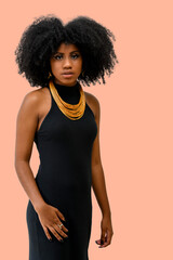 Wall Mural - portrait of a beautiful black girl with an afro hairstyle wearing a black dress and a big necklace, fashion concept