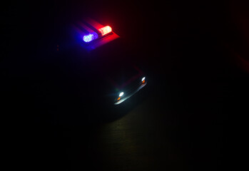 Wall Mural - Police car chasing a car at night with fog background. 911 Emergency response police car speeding to scene of crime. Selective focus