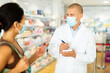 © JackF - Pharmacist in protective mask writes in notebook the name of the drugs that the buyer tells him to