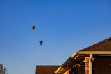 Fototapeta Lawenda - Hot air balloon flying over a community