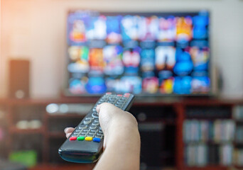 The man pressing button on TV remote control.