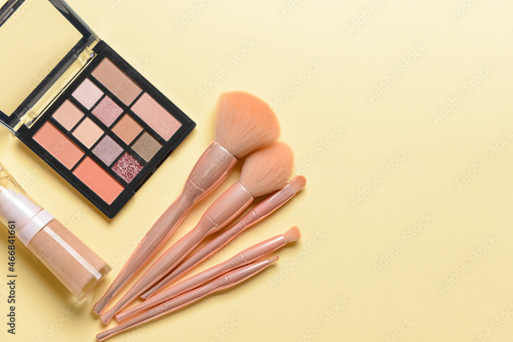 Set of professional makeup brushes with decorative cosmetics on color background