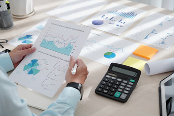 Wall Mural - Closeup image of financial analyst examining document with various charts indicating company performance