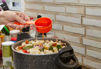 Poster - The chef pours oil into casserole on gas stove with vegetables for the soup and pieces of baguette