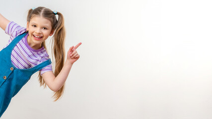 Wall Mural - A little girl points her hand at the advertisement. White isolated background.