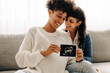 © (JLco) Julia Amaral - Same-sex pregnant couple holding up their ultrasound scan
