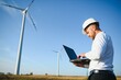 © Serhii - Young engineer man looking and checking wind turbines at field