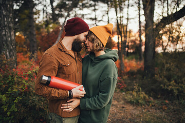 Wall Mural - Happy couple in love drinking tea from thermos in beautiful autumn forest.