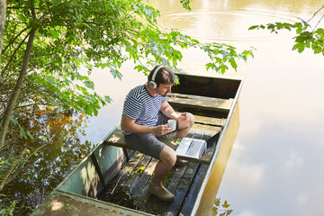 Man with a cup of coffee on the laptop PC at the lake