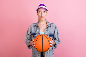 Wall Mural - Photo of impressed young sporty lady hold ball wear jeans shirt cap isolated on pink color background