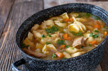 Wall Mural - Pot with chicken noodle soup. Cooked with tortellini