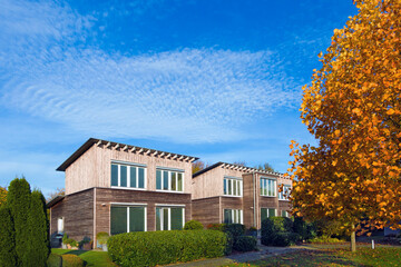 modernes mit Lärche vertäfeltes zweiteiliges zweigeschossiges Holz-Passivhaus mit Pultdach im Herbst