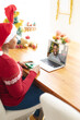 © vectorfusionart - African american woman in santa hat making laptop christmas video call with smiling male friend
