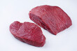 Raw dry aged bison beef rump steak slices offered as close-up on white background with copy space - free-form select