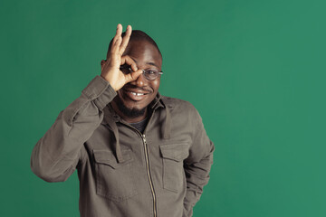 Wall Mural - One young stylish african man wearing casual clothes isolated on dark green studio background. Emotions, facial expression concept.