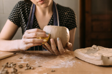 Woman potter works with clay in her home workshop, hands of the master close-up, kneads and sculpts clay before work, selective focus. creative hobby